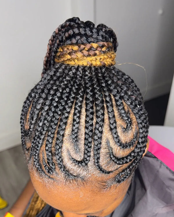 Kate's curved feed-in cornrows seen from above, sweeping up into a high ponytail wrapped in honey blonde