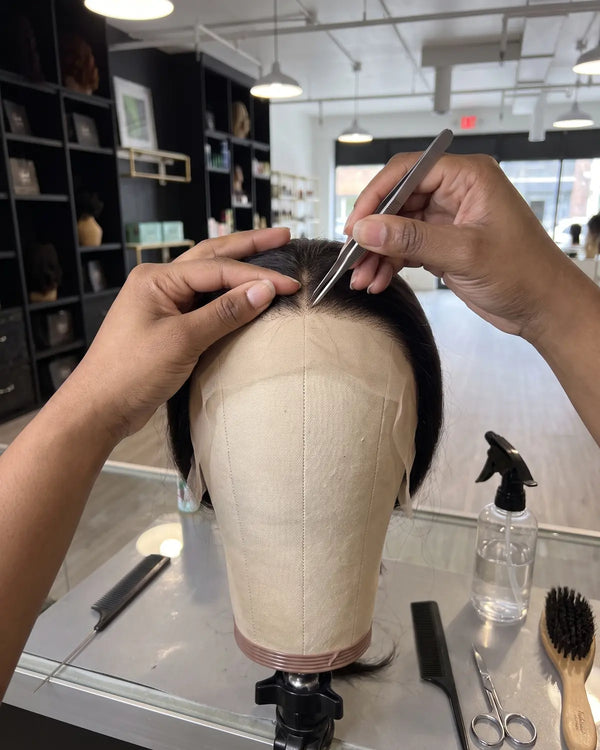 A stylist plucking the hairline of a lace wig during wig customization at Lovely Hair in West Des Moines